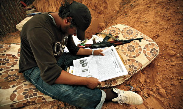 A rebel fighter reads a newspaper at Misrata's western front line