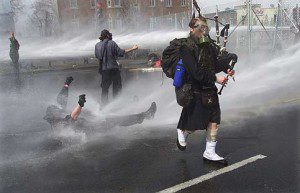A bagpiper plays while a protester gets blasted photo by Tom Hanson, courtesy of Canadian Press